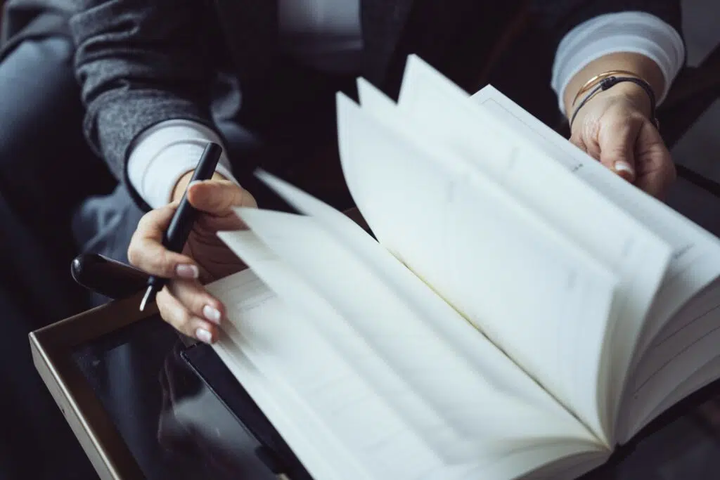 Detail of a woman's hands flipping through a TIMEMASTER notebook.